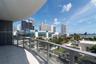 Curved balcony with glass railing, tile flooring, and urban skyline with water backdrop