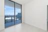 Expansive sliding glass doors, balcony with glass railing, light tile flooring, and white walls