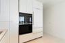 Integrated wall oven, white cabinetry, built-in refrigerator, sleek hardware, and light-toned tile flooring