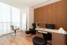 Wood-finish flooring throughout, full-height windows with sheer drapery, wood-panel accent wall, and a built-in desk with an integrated task light