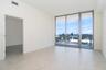 Sliding glass doors opening to a balcony with metal railings, tile flooring, and white walls