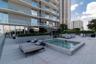 Rooftop amenity deck featuring a built-in spa, expansive tiled patio, and integrated planters with mature landscaping