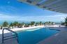 Rooftop pool with clear glass railing, surrounding planters, and a wide-slat pergola