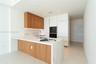Modern kitchen featuring a waterfall island with wood-finish paneling, under-cabinet lighting, integrated appliances, and a marble-finish backsplash