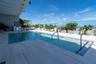 Rooftop swimming pool with integrated spa, glass safety barrier, and an array of potted plants