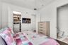 White walls featuring a built-in closet system, dark wood-finish flooring, and a ceiling fan