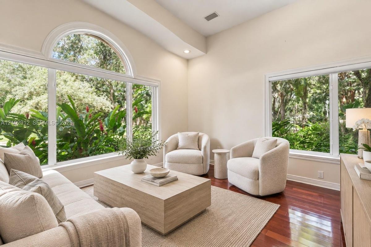 Vaulted ceiling with recessed lighting, expansive windows, large arched transom window, wood-finish flooring, and a neutral color palette