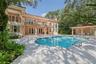 Expansive pool deck with a freeform swimming pool, outdoor kitchen, and a two-story residence featuring multiple balconies
