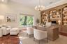 Wood-finish flooring, built-in shelving with integrated lighting, vaulted ceiling, large window, and a chandelier