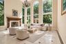 Soaring ceilings, arched windows, carved wood fireplace mantel, marble tile flooring with contrasting accents, and a tiered chandelier