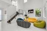 Soaring ceilings with upper windows, white tile flooring, dark wood-finish staircase, and stainless steel railings