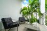 Outdoor balcony featuring a contemporary metal railing, light-toned flooring, and lush tropical foliage