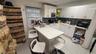 White cabinetry with modern hardware, dark tile backsplash, stainless steel sink with pull-down faucet, and white countertop island