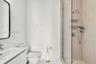 Modern vanity with integrated sink, sleek wall-mounted mirror, contemporary toilet, and a glass-enclosed shower with pebble-tiled flooring