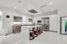 White gloss cabinetry, stainless steel appliances, central island with seating, white tile flooring, and recessed lighting