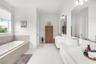 Integrated soaking tub with wood-finish surround, dual floating vanities with integrated rectangular sinks, extensive wall-mounted mirror, and tile fl