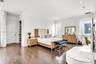 Dark wood-finish flooring, recessed lighting, white walls, multiple windows, and a built-in closet with shelving