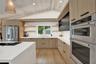 Kitchen with vaulted ceiling, wood-finish beams, stainless steel appliances, white countertops, and wood-finish flooring