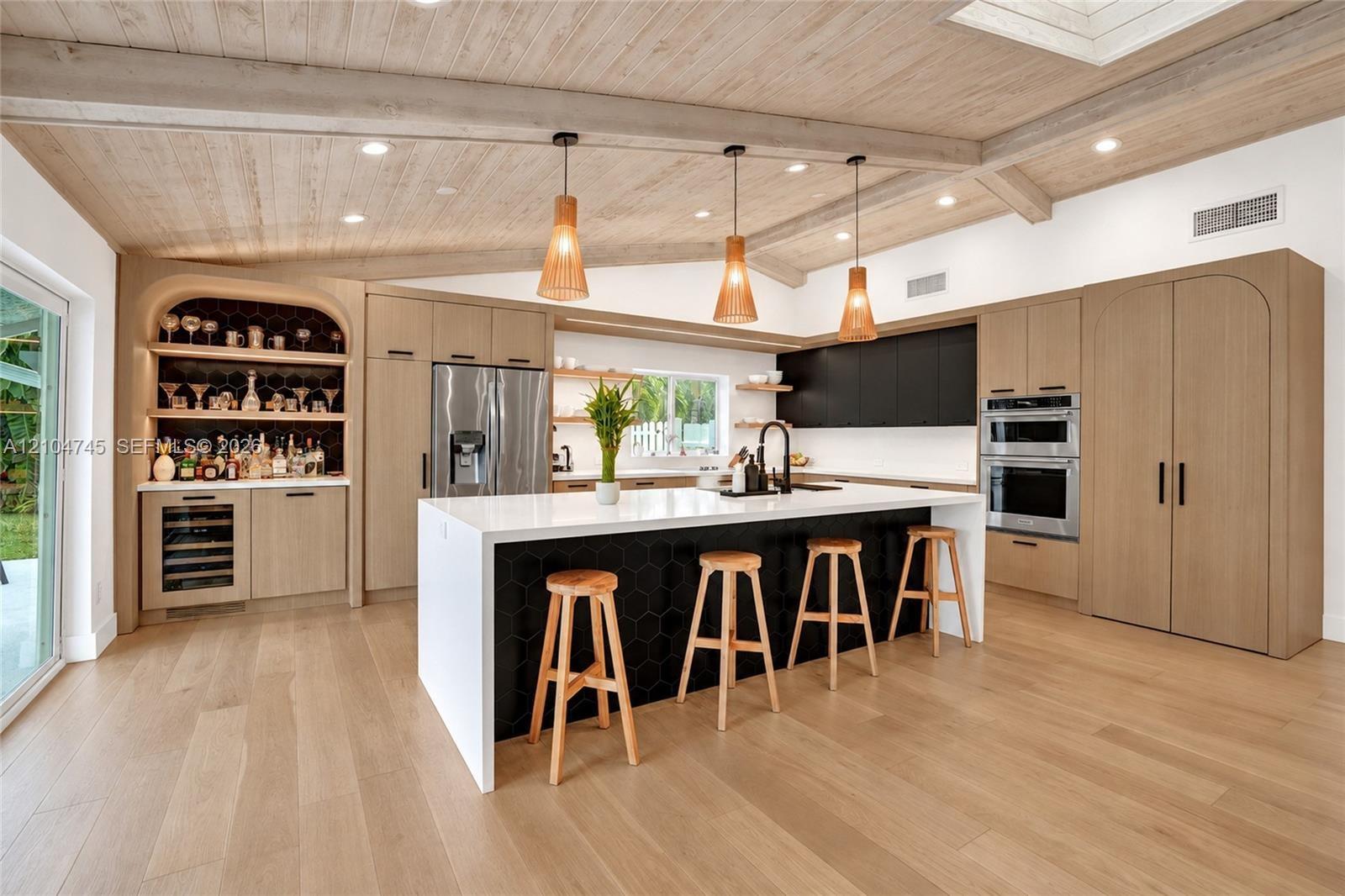 Wood-finish flooring, vaulted wood-paneled ceiling with exposed beams, built-in cabinetry with integrated appliances, kitchen island with hexagonal ti