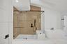 Spacious shower enclosure with glass panels, light wood-finish wall, and black fixtures