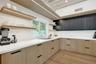 Contemporary kitchen featuring light wood-finish cabinetry, dark upper cabinetry, white countertops, and a hexagon tile backsplash