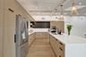 Spacious kitchen featuring light wood-finish cabinetry, stainless steel appliances, a large center island with a sink, white countertops, and wood-fin