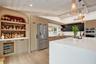 Kitchen featuring wood-finish flooring, white vaulted ceiling with exposed beams, light wood-finish cabinetry, a large kitchen island with a white cou