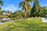 Expansive lawn with mature landscaping, cable railing fence, and a visible pool area