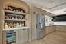 Kitchen featuring light wood-finish flooring, light wood-finish cabinetry, stainless steel refrigerator, white countertops, and a built-in bar area wi
