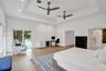Recessed tray ceiling with integrated lighting, wood-finish flooring, dual ceiling fans, and sliding glass door