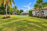 Expansive lawn with mature palm trees, a swimming pool, and a poolside gazebo