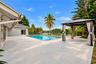 Expansive outdoor living area featuring a rectangular swimming pool, spacious pool deck, and a detached gazebo with privacy drapes, set against a wate
