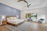 Tray ceiling with recessed lighting, wood-finish flooring, accent wall, ceiling fans, and large window overlooking a body of water