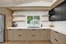 Integrated stainless steel refrigerator, light wood-finish lower cabinetry, white solid surface countertops, black upper cabinetry, and a built-in coo