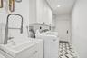 Utility room featuring a built-in sink with a pull-down faucet, upper and lower cabinetry, a patterned tile floor, and a flush-mount ceiling light