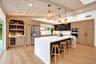 Vaulted wood-finish ceiling with exposed beams, wood-finish flooring, stainless steel appliances, built-in shelving with integrated lighting, and a ki