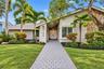 White stucco exterior with stone accents, featuring a gray paver walkway