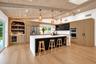 Expansive kitchen featuring a large island, wood-finish flooring, custom cabinetry, integrated appliances, and a built-in bar with beverage refrigerat