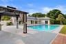 Rear exterior featuring a swimming pool, expansive concrete patio, and a covered gazebo