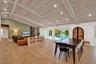 Vaulted ceiling with exposed wood beams, recessed lighting, wood-finish flooring, and sliding glass doors opening to the exterior