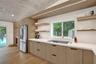 Vaulted wood-finish ceiling, light wood-finish cabinetry, stainless steel appliances, integrated cooktop, and light countertops