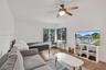 Hardwood-finish flooring, corner windows with blinds, recessed lighting, ceiling fan with integrated light, and a white storage unit