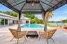 Outdoor covered patio with string lighting, expansive pool area, and direct water frontage