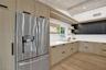 Stainless steel French door refrigerator, light wood-finish cabinetry, dark upper cabinetry, white countertops, and light wood-finish flooring