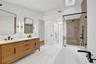Dual vanity with wood-finish cabinetry, white countertop, and matte black fixtures