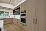 Kitchen featuring a vaulted wood-paneled ceiling, integrated stainless steel appliances, light wood-finish cabinetry, white countertops, and wood-fini