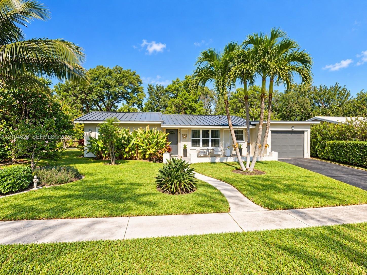 Single-story residence featuring a metal roof, attached garage, and a concrete pathway