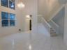 Double entry doors with gold-tone hardware, tile flooring, and a crystal chandelier