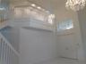 Two-story foyer featuring a double staircase with white balusters, two crystal chandeliers, and loft overlooks social areas - loft is an added bonus t