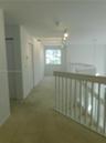 Staircase featuring white wood railings and carpeted treads, with tile flooring at the base and leading to upstairs bedrooms and loft.